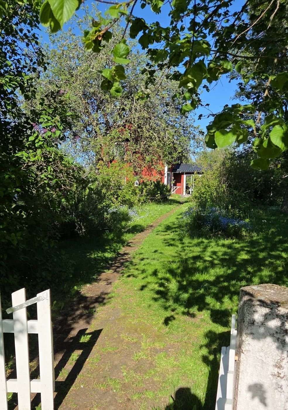 Grässtig genom trädgården fram till det röda boningshuset